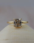 Low profile Asscher cut diamond claw solitaire engagment ring featuring delicate floral scroll along the side of the setting.