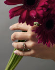 Esme hexagon-shaped- salt and pepper diamond engagement ring with tapered baguette diamonds worn on a woman's hand holding a flower.