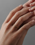 Hand-engraved fern pattern on a thin Fairmined yellow gold wedding band worn on a women's finger.