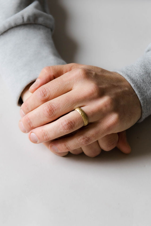 Close up of model hand wearing the mens Hammer wedding band in yellow gold
