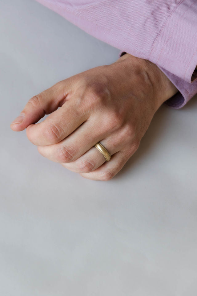 Close up of models hand wearing the mens Milgrain wedding band in gold 2