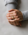 Close up of model hand wearing the mens Organic wedding band in gold