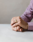 Close up of model hand wearing the mens Wave wedding band in yellow gold