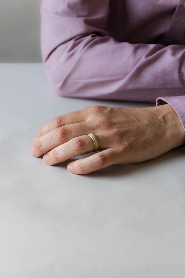 Close up of model hand wearing the mens Woodgrain wedding band in yellow gold 2
