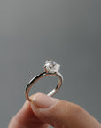 Close-up of women's fingers holding the Myra compass platinum claw solitaire with an Old European cut diamond.