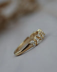 Side close-up of the Navette diamond cluster wedding band showing round and marquise diamonds in a gold setting.
