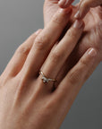 Close-up of a woman wearing the Trillium curved gold wedding band with marquise and round diamonds.