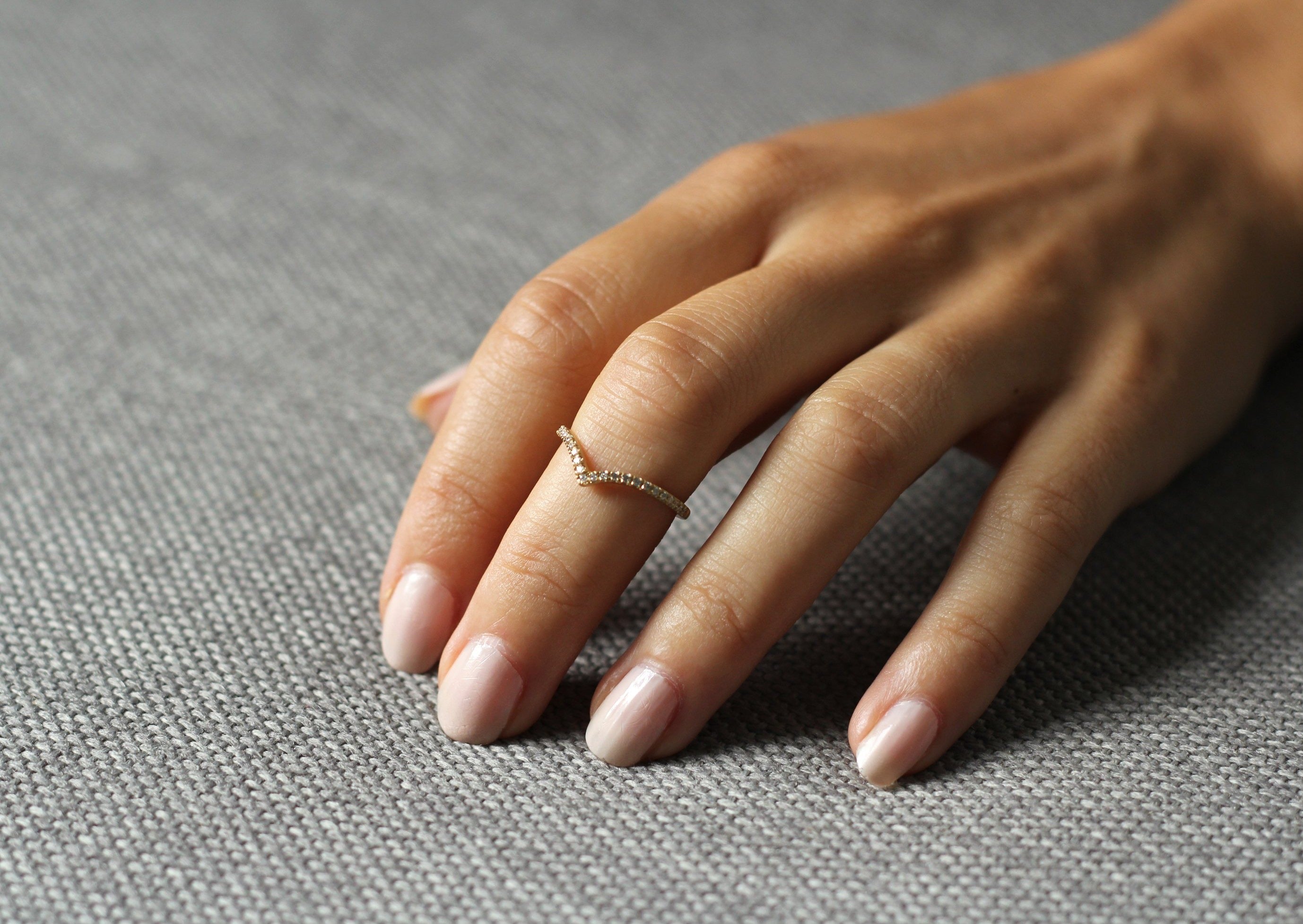 Close up of model hand wearing the Chevron Mia womens wedding band by Fluid Jewellery in yellow gold 2