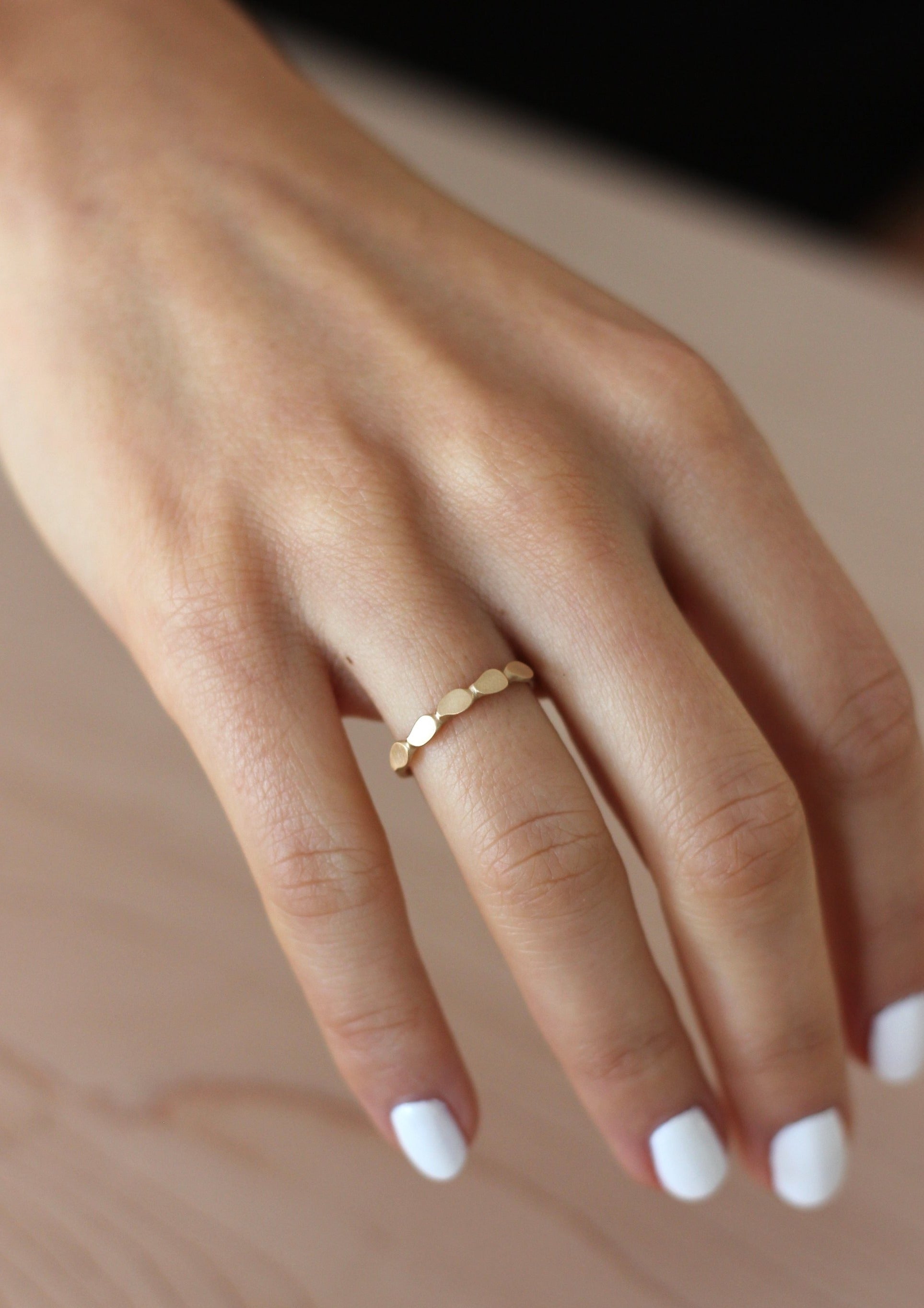 Close up of model hand wearing the Lotus womens wedding band by Fluid Jewellery in gold