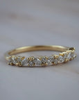 Marissa yellow gold wedding band featuring a row of marquise and round diamonds, photographed on a light gray marble surface.