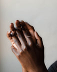 Close up of model hand wearing the curved Caia womens wedding band by Fluid Jewellery in yellow gold 2