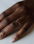 Close up of model hand wearing the curved Caia womens wedding band by Fluid Jewellery in yellow gold 3