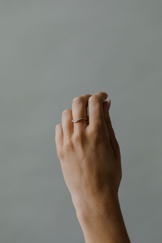 Close up of model hand wearing the curved Ida womens wedding band by Fluid Jewellery in gold