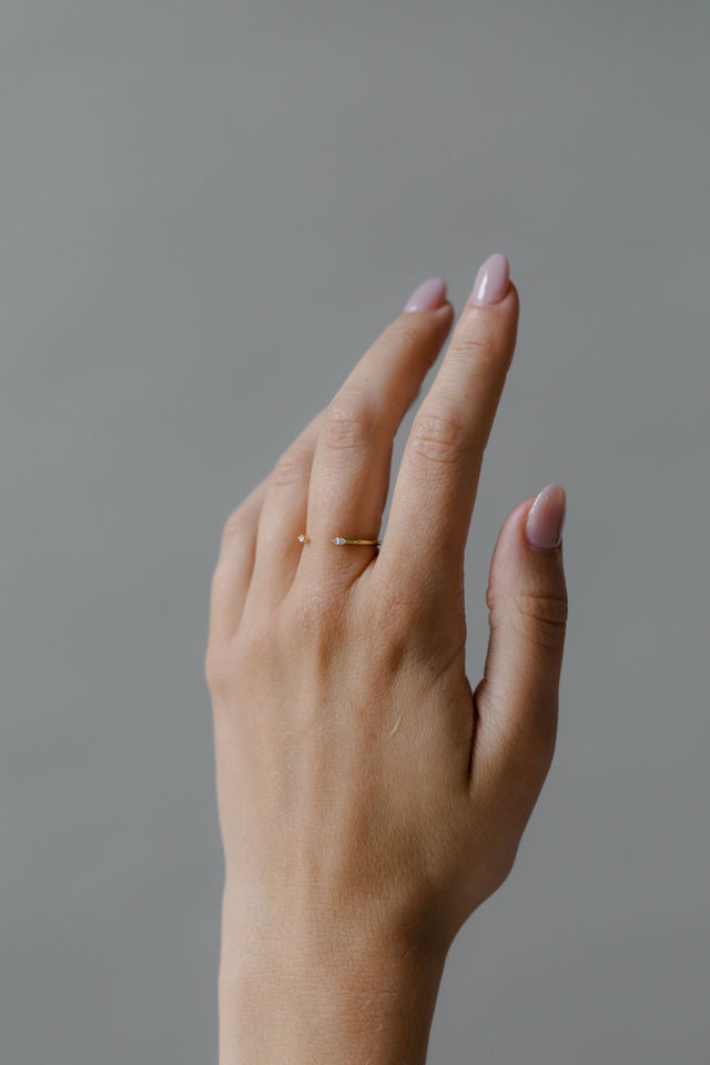 Close up of model hand wearing the open Mara womens wedding band by Fluid Jewellery in yellow gold