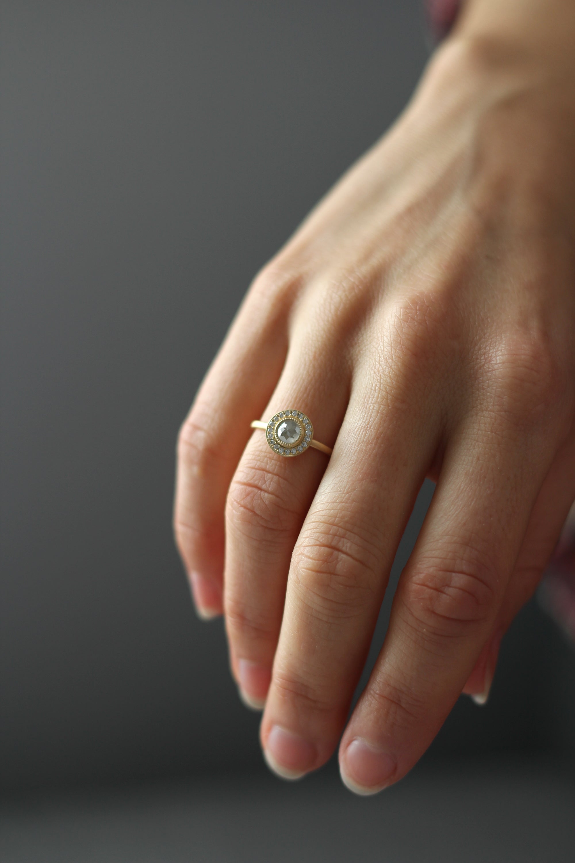 Model wearing the Halo Aura Solitaire Engagement Ring in yellow gold by Fluid Jewellery 2
