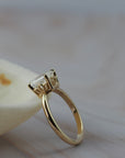 Close-up side detail of an Asscher cut diamond claw solitaire showing the delicate floral scroll design on the low-profile setting.