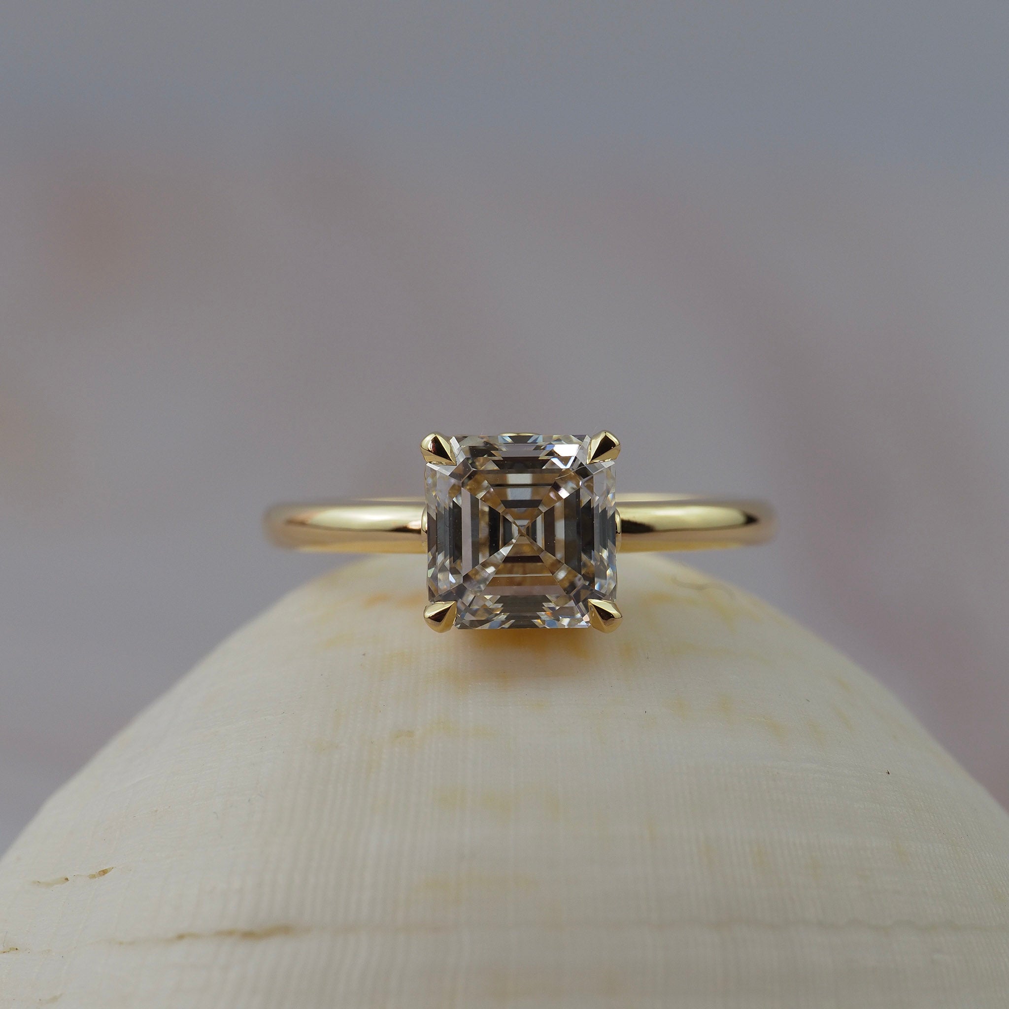 Low profile Asscher cut diamond claw solitaire engagment ring featuring delicate floral scroll along the side of the setting. 