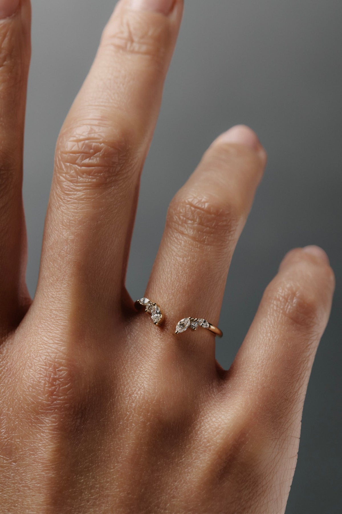 Close-up of the Aster diamond band worn on a women's finger, featuring marquise and round diamonds inspired by aster flowers.