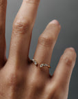 Close-up of the Aster diamond band worn on a women's finger, featuring marquise and round diamonds inspired by aster flowers.