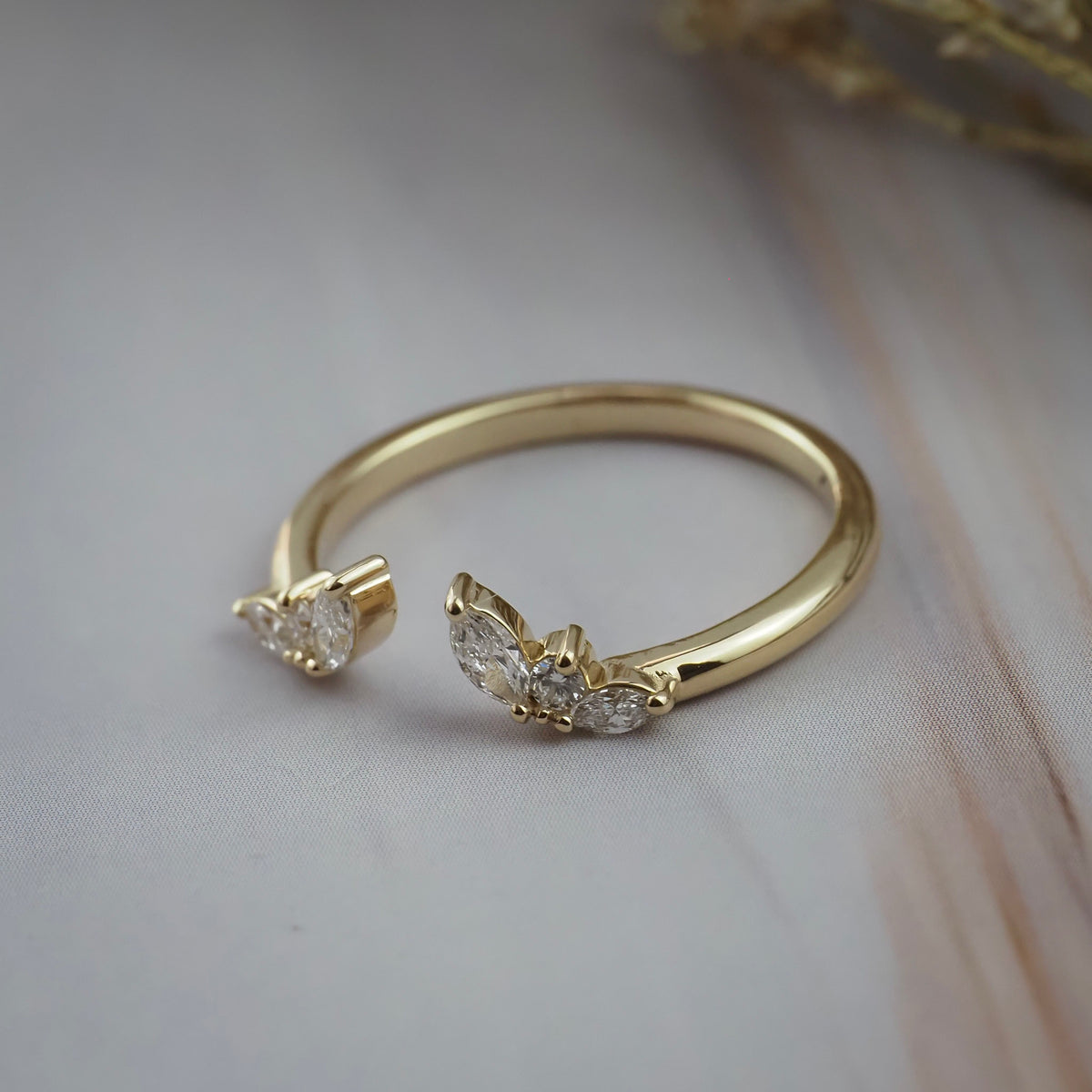 Side close-up of the Aster open guard wedding band showing marquise and round diamonds in a flower inspired gold setting.