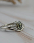 Close-up of the Celeste teal sapphire and diamond cluster engagement ring paired with a curved gold wedding band.