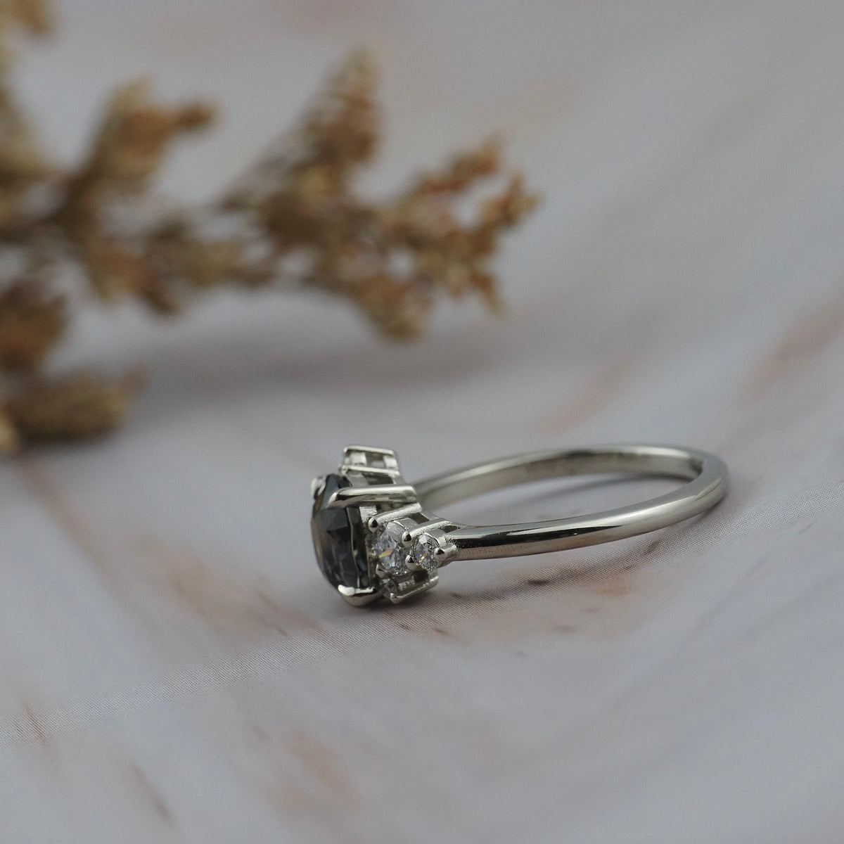 Side profile of the Celeste teal sapphire and diamond cluster engagement ring showing a close of the side of the gold setting.