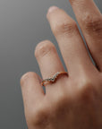 Close-up of the Claudia chevron wedding band in Fairmined gold with delicate diamonds worn on a woman's ring finger. 
