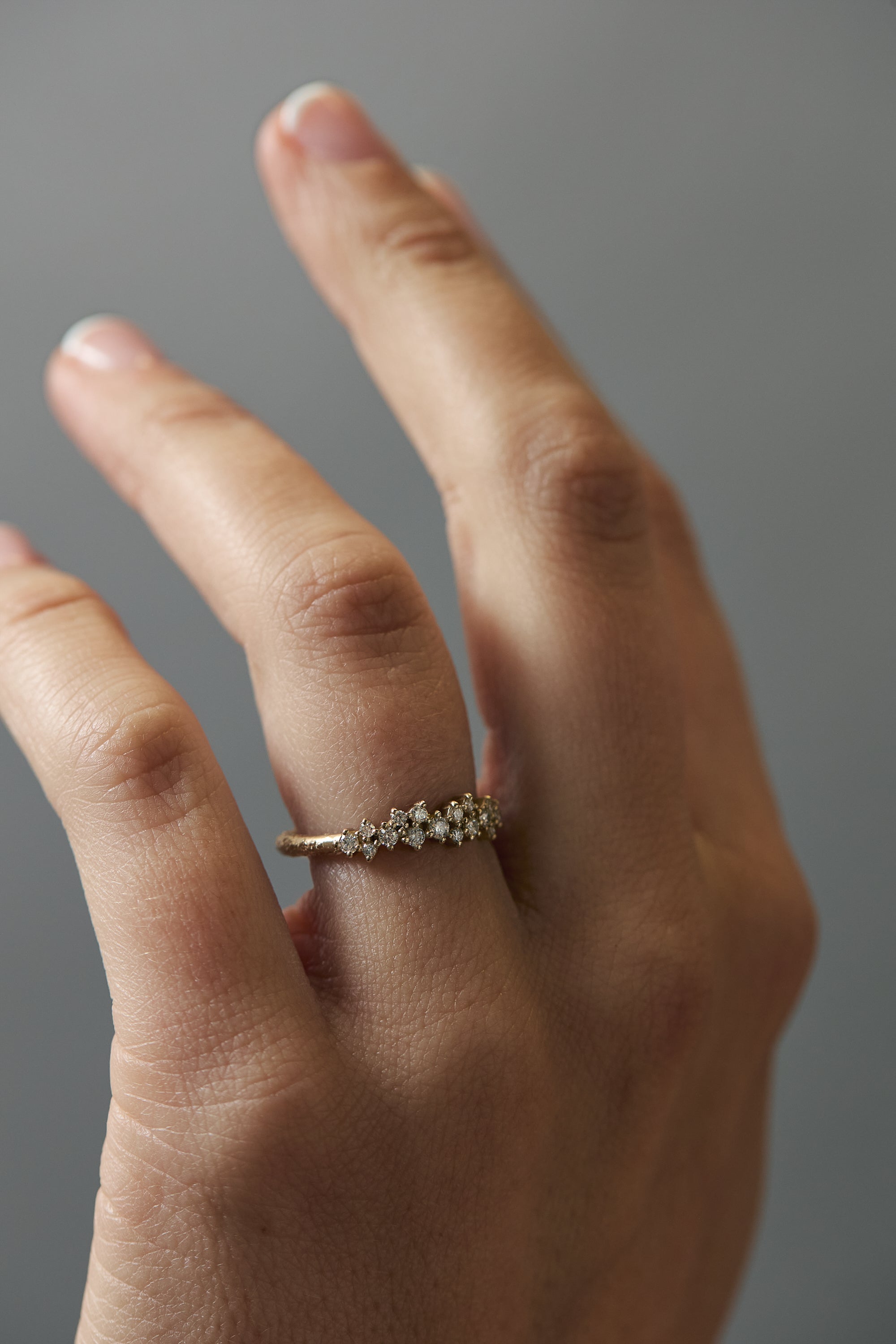 Close-up of the Constellation diamond gold wedding band worn on a woman's finger, featuring delicate scattered diamonds.