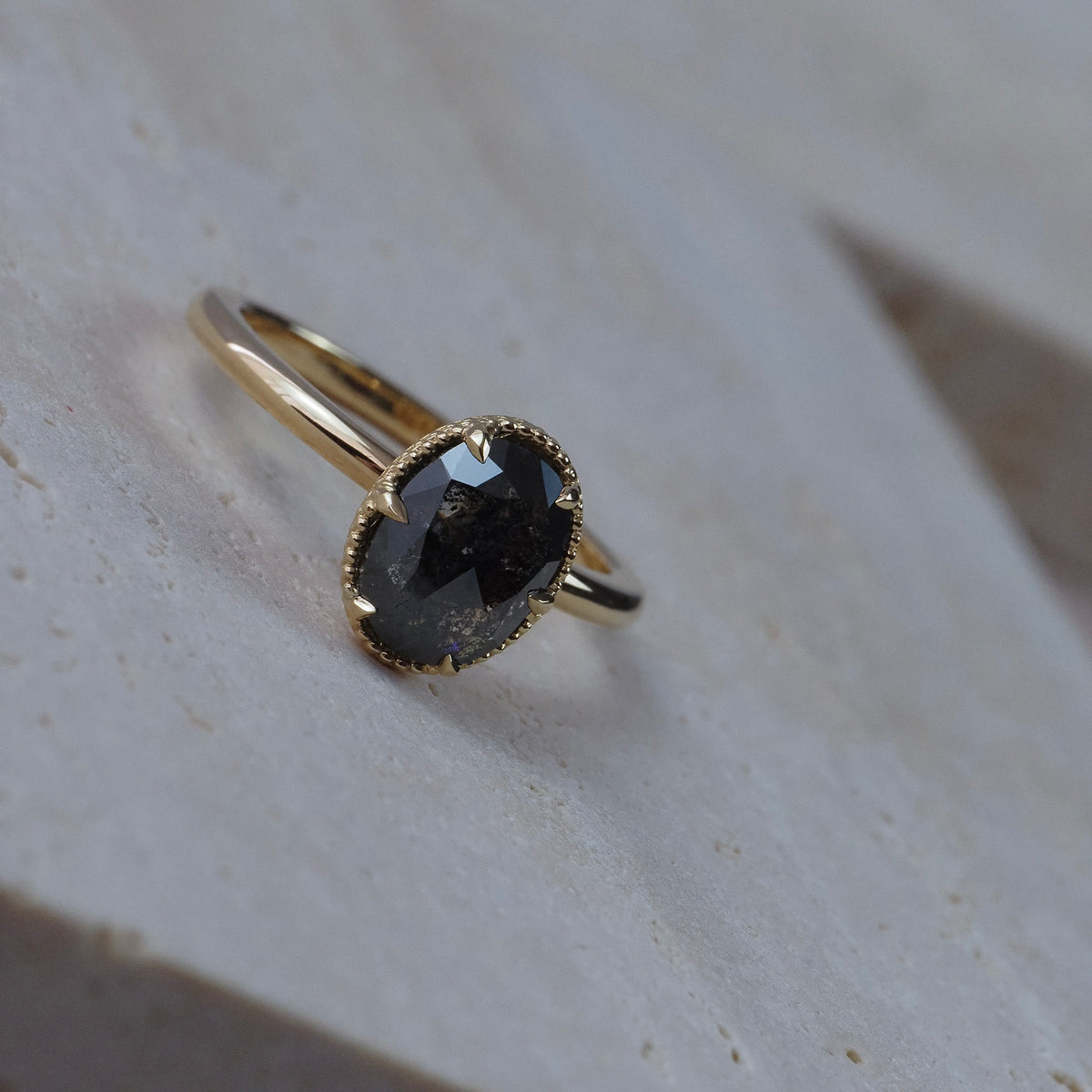 Elanor salt and pepper oval diamond six-claw solitaire with an Art Deco woven basket setting and migrained edge.