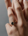Close-up of the Elanor salt and pepper oval diamond six-claw solitaire worn on a woman's finger.