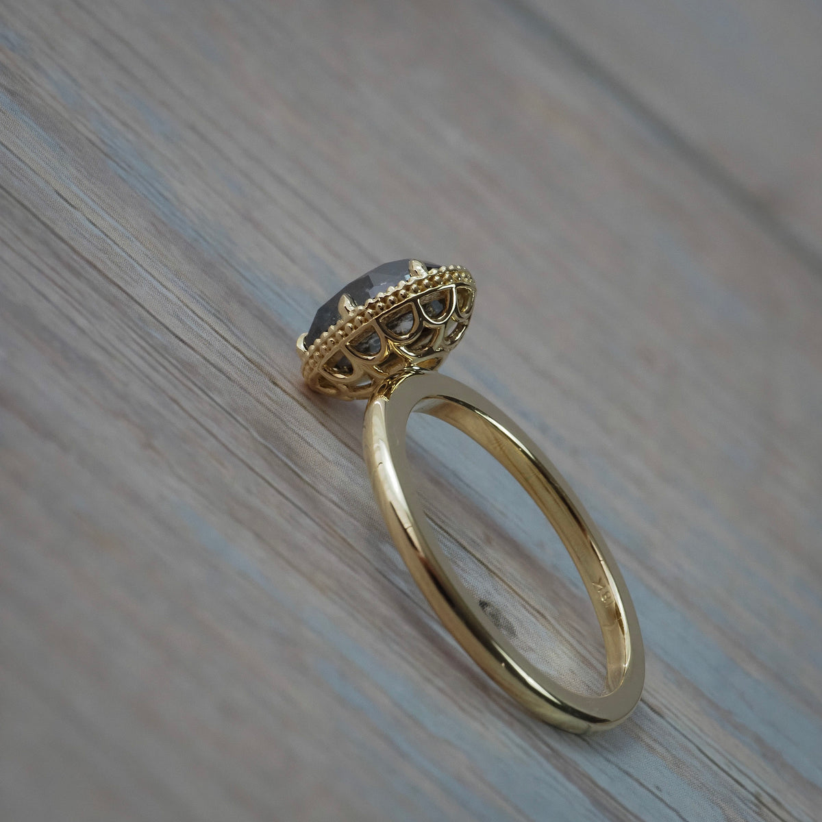 Close-up side and back view of the Elanor salt and pepper oval diamond solitaire showing its Art Deco women's basket setting, and double milgrained beaded edge.