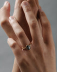 Stylized close-up of women's hands wearing the Elanor salt and pepper oval diamond six-claw solitaire with an Art Deco woven basket and beaded edge.
