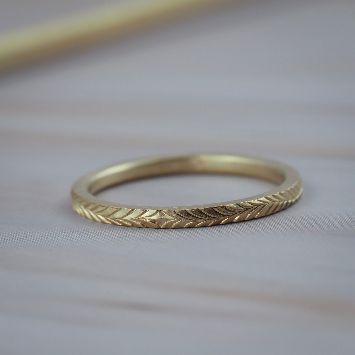 Thin Fairmined yellow gold wedding band featuring hand-engraved fern details.