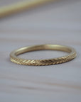 Thin Fairmined yellow gold wedding band featuring hand-engraved fern details.