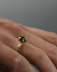 Close-up side view of the Fern hand-engraved green sapphire solitaire on a woman's hand, highlighting the detailed Fairmined gold band and setting.