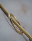 Close up side view of hand-engraved fern details on a thin Fairmined yellow gold wedding band.
