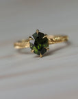 Fern hand engraved solitaire engagement ring featuring a step-cut oval green sapphire in Fairmined gold.
