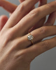 Close-up of the Flora gold milgrain bezel solitaire with an Old European cut diamond and floral side engravings worn on a woman's finger.