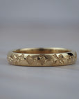 Close-up of hand engraved poppy flowers on a Fairmined yellow gold wedding band.
