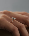 Close-up side profile of Lana six claw solitaire engagement ring worn on a woman's finger, showing the moval shaped antique cut Old European diamond  and two-tone platinum and rose gold setting.
