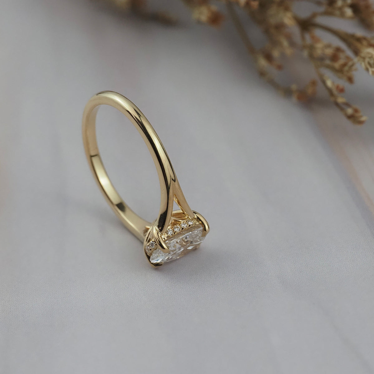 Close-up side view of the Love Knot split shank diamond solitaire engagement ring resting on its side, showing the hidden halo and split shank band.