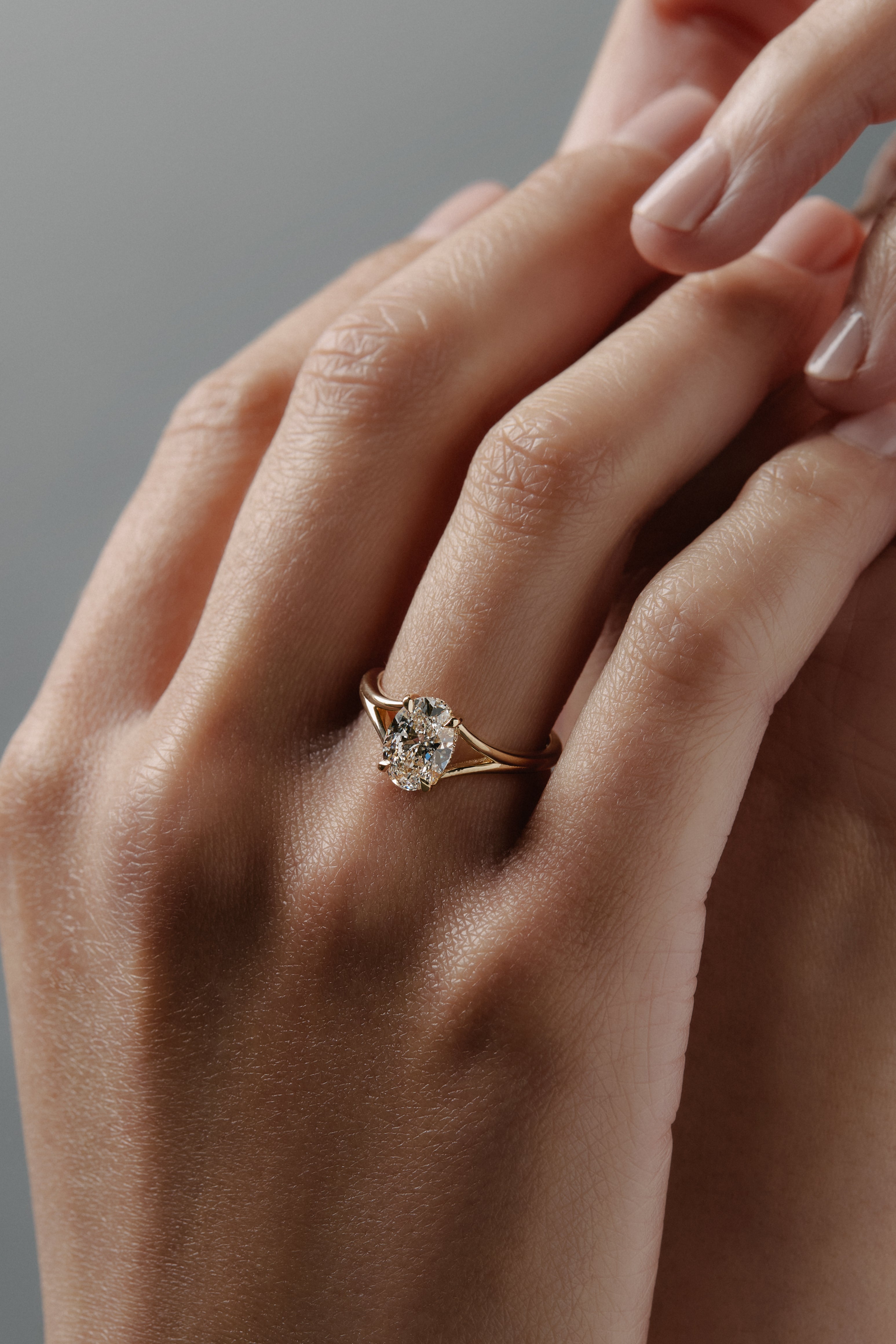 Love Knot split shank diamond solitaire engagement ring featuring a hidden halo and intertwined gold setting on hand.