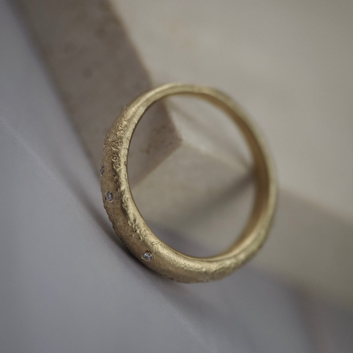 Close-up side profile of the textured Fairmined yellow gold finish and Canadian diamonds on the Luna wedding band.