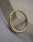 Close-up side profile of the textured Fairmined yellow gold finish and Canadian diamonds on the Luna wedding band.