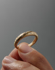 Close-up of women's hands holding the Luna textured yellow gold wedding band featuring small diamonds.