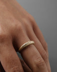 Close-up of a women wearing the Luna textured yellow gold wedding band with delicate Canadian diamonds on her finger.
