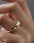 Close-up side view of the Magnolia half bezel solitaire on a woman's finger, highlighting  the hand engraved magnolia flowers and detailed diamond setting.