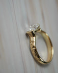 Close-up side view of the Magnolia half-bezel solitaire showing the detailed setting and hand engraved magnolia flowers along the band.