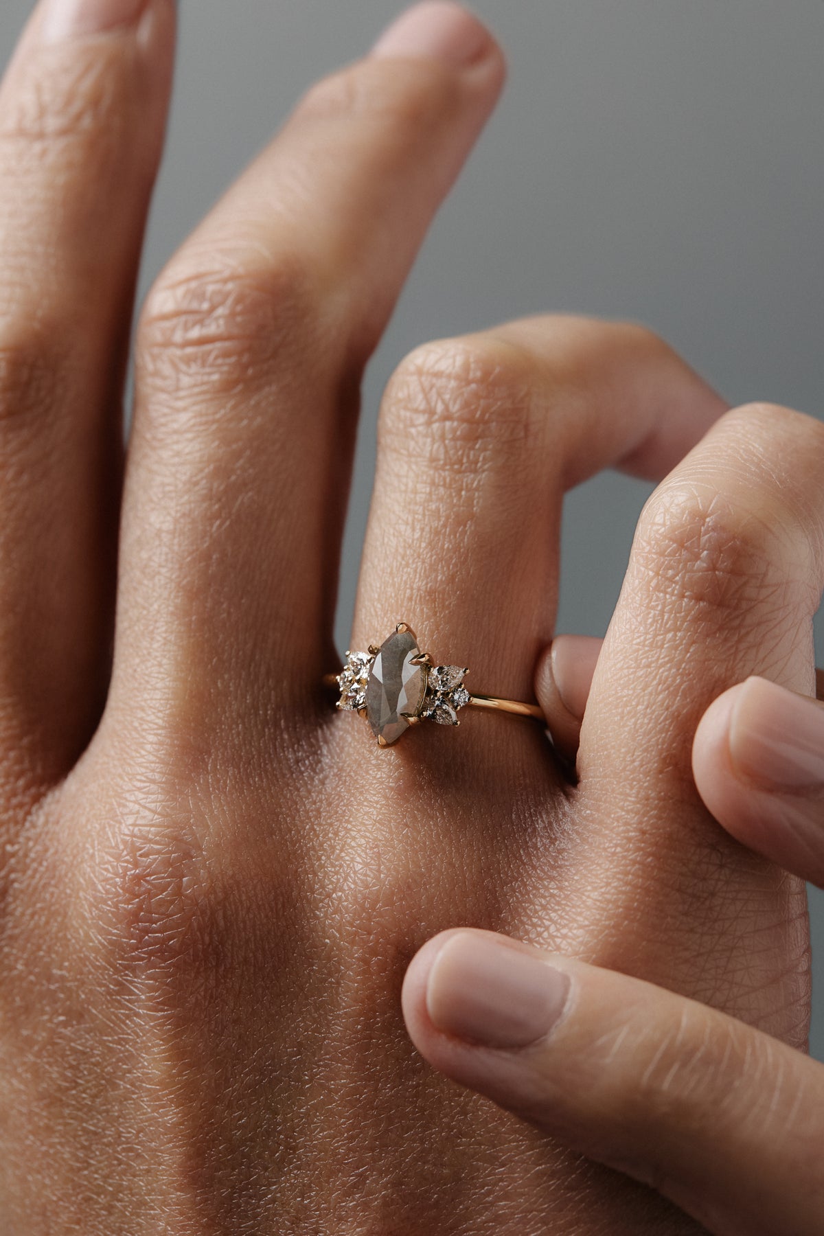 Close-up of the Meghan salt and pepper marquise-shaped rose cut cluster engagement ring worn on a woman's finger.