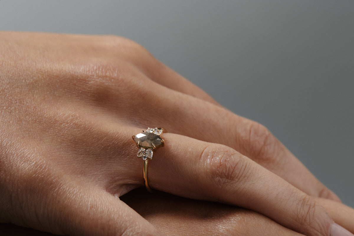 Close-up of the Meghan salt and pepper marquise shaped rose cut cluster engagement ring worn on a woman's finger.